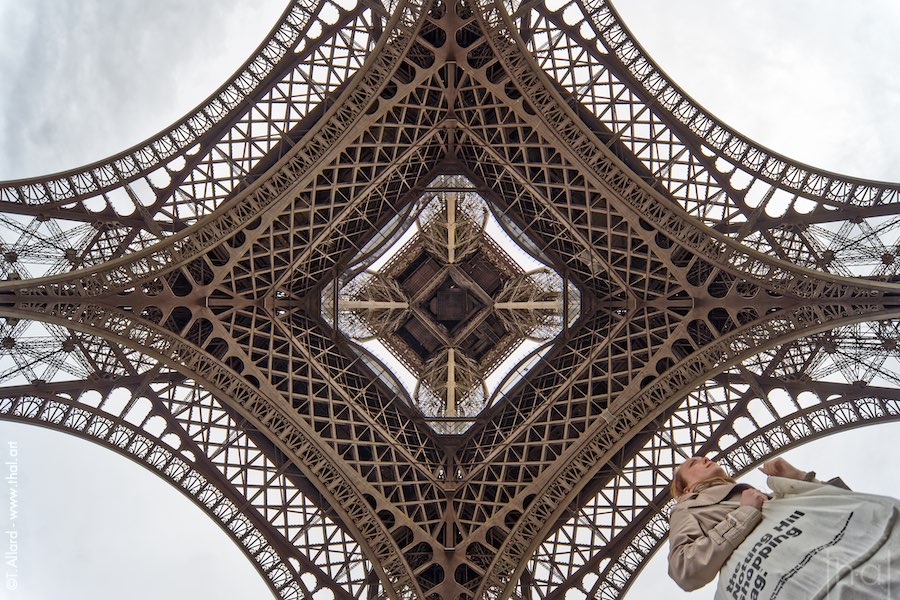 Wide-angle view of the Eiffel Tower from below with a passer-by