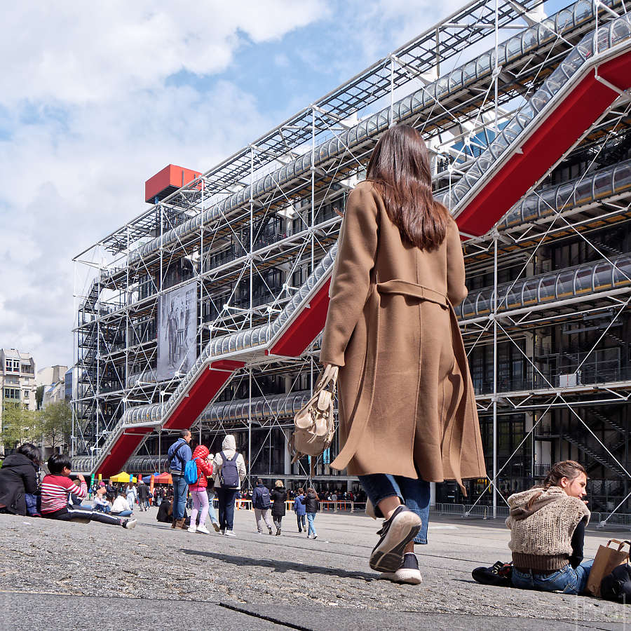femme de dos marchant sur la place du Centre Pompidou à Paris