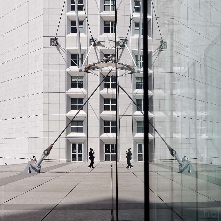 réflexion d'une passante sur les murs de verre sous la Grande Arche